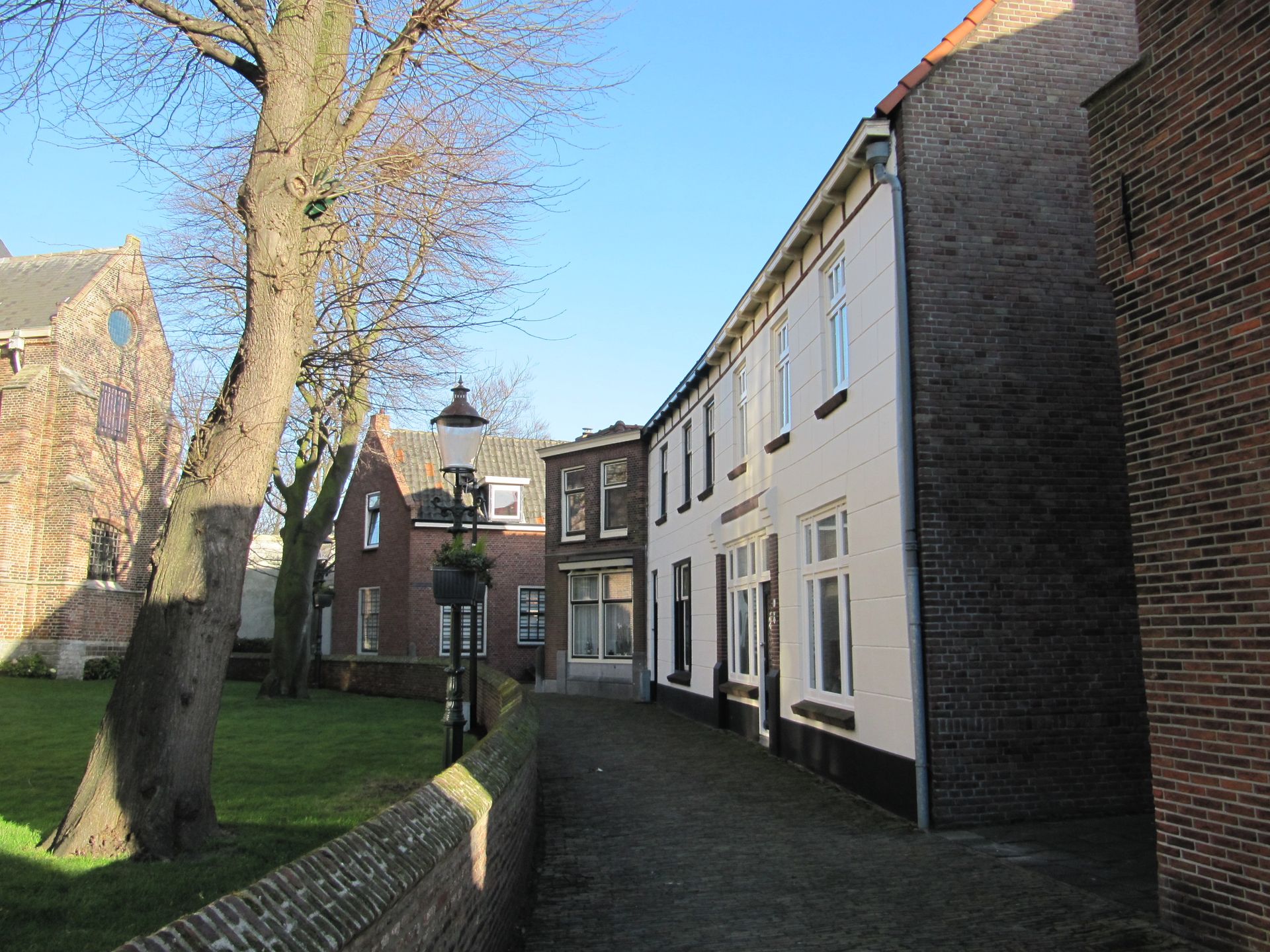 Foto van de Kerkstraat in Naaldwijk waar de moord ongeveer gepleegd moet zijn geweest. Rechts de poort die net na de moord werd gerealiseerd en die daarna volgens de overlevering ook wel de bloedpoort werd genoemd.